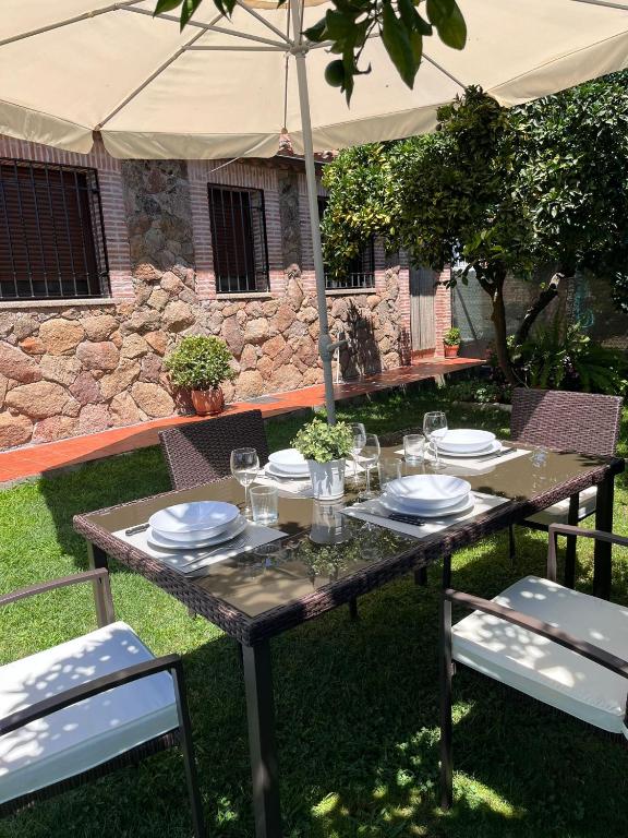 a table with plates and glasses and an umbrella at El huerto de Lino in Candeleda