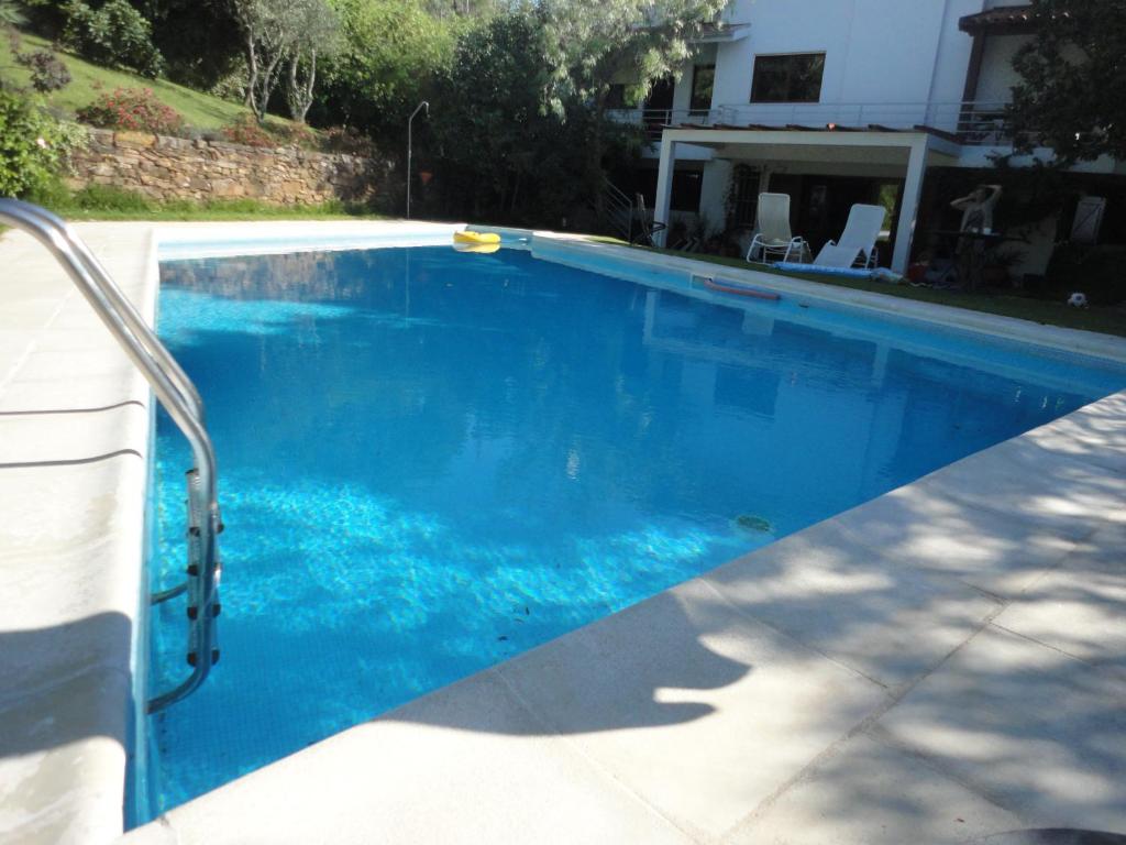a swimming pool with blue water in front of a house at Cork Tree Villa in Gondomar