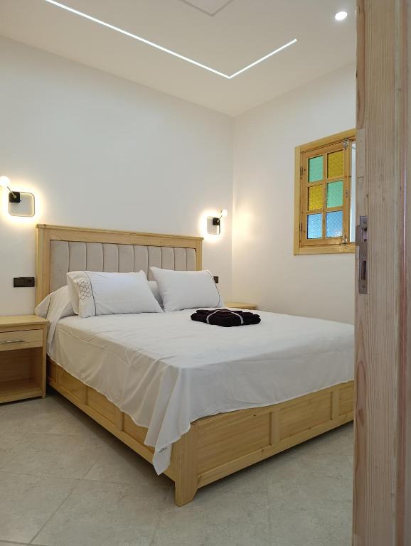 a bedroom with a large bed with white sheets and a window at Stay with dkouk in Akchour