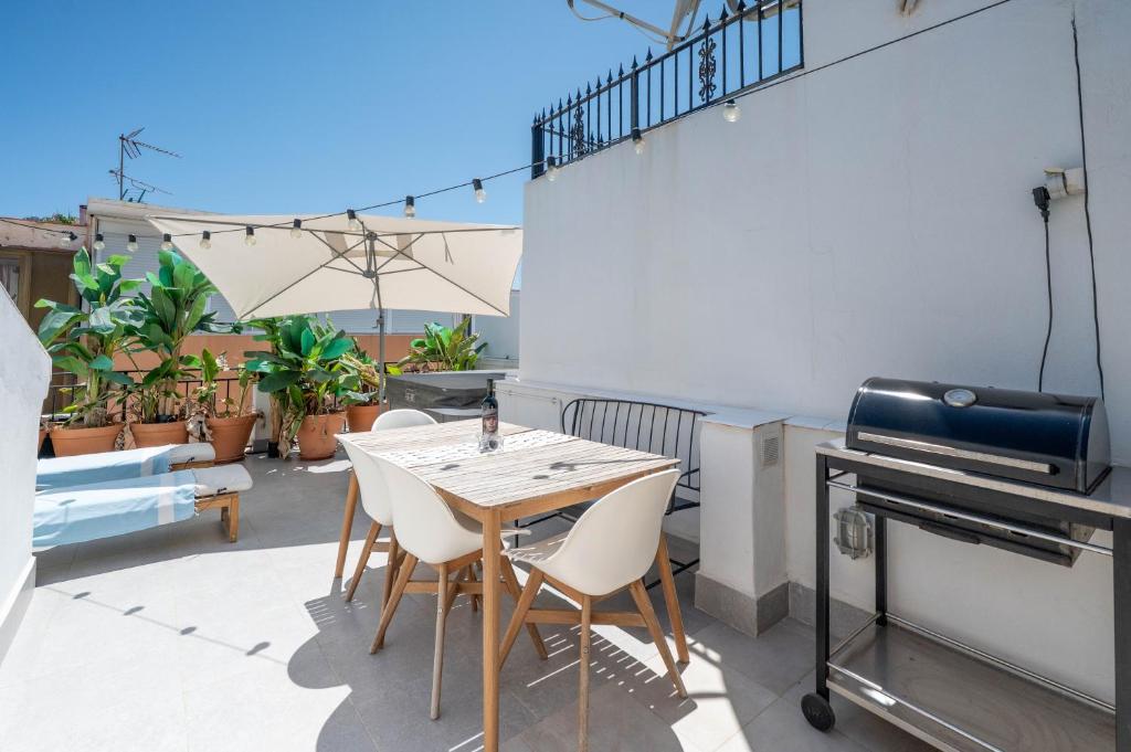 a patio with a table and chairs and a grill at Charming Seaside Home with Jacuzzi & Terrace in Málaga