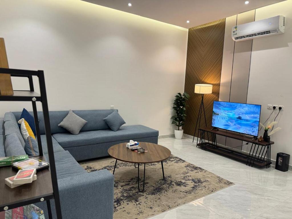 a living room with a blue couch and a tv at شقق الدانة وصول ذاتي in Hafr Al Baten