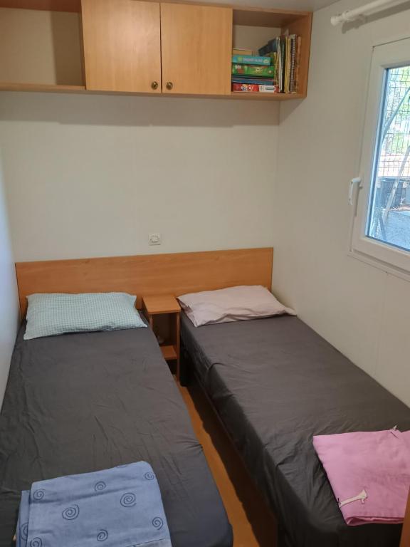 two beds in a room with a desk and a window at Family mobile home solar powered near the sea and the airport in Áyios Spirídhon