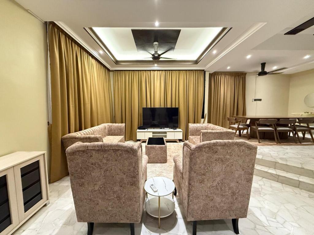 a living room with chairs and a flat screen tv at White House - Alor Setar in Alor Setar