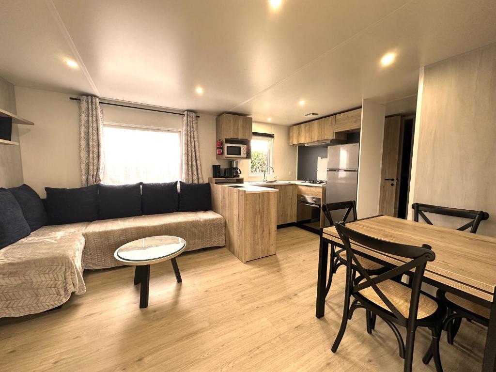 a living room with a couch and a table at Les Charmettes Mobilhome Neuf 3 ch - 2 sdb climatisé - Locsweethome in Les Mathes