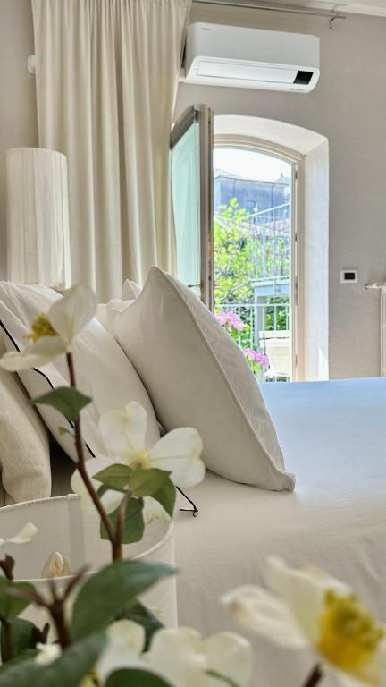 a bedroom with a bed with white pillows and a window at Borgo dei Sogni - Deluxe Apartment - Lago di Garda in San Felice del Benaco