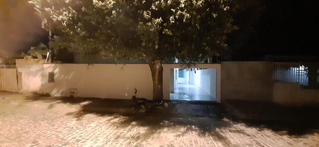 a tree in front of a white fence with a door at Casa Recanto do aconchego - Ao lado do centro in Bom Jesus da Lapa