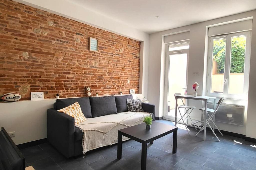 un salon avec un canapé et un mur de briques dans l'établissement Providence Terrasse privée - Proche Gare Sncf, à Toulouse