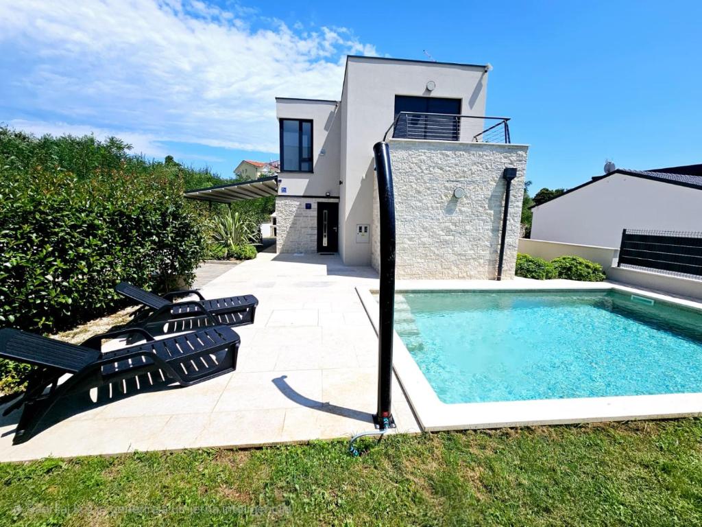 a backyard with a swimming pool and a house at Villa Green s bazenom in Medulin