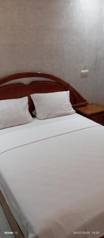 a bed with white sheets and pillows on it at Appart Family Agadir Hay mohammadi in Agadir