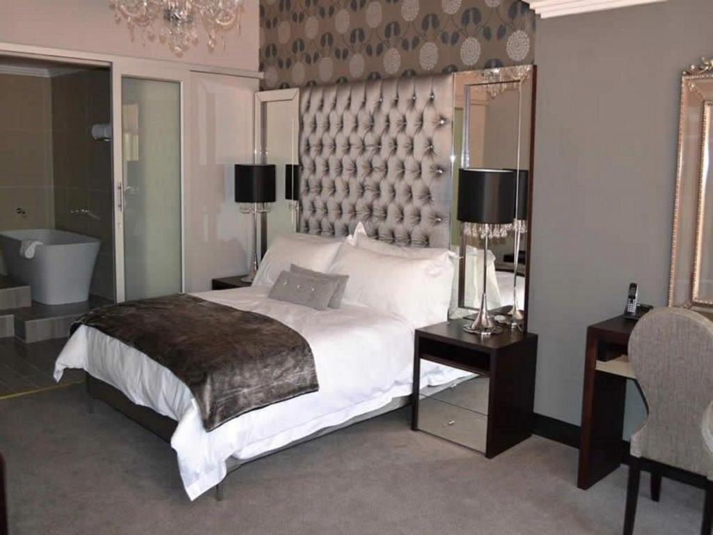 a bedroom with a large bed and a bath tub at President Hotel in Bloemfontein