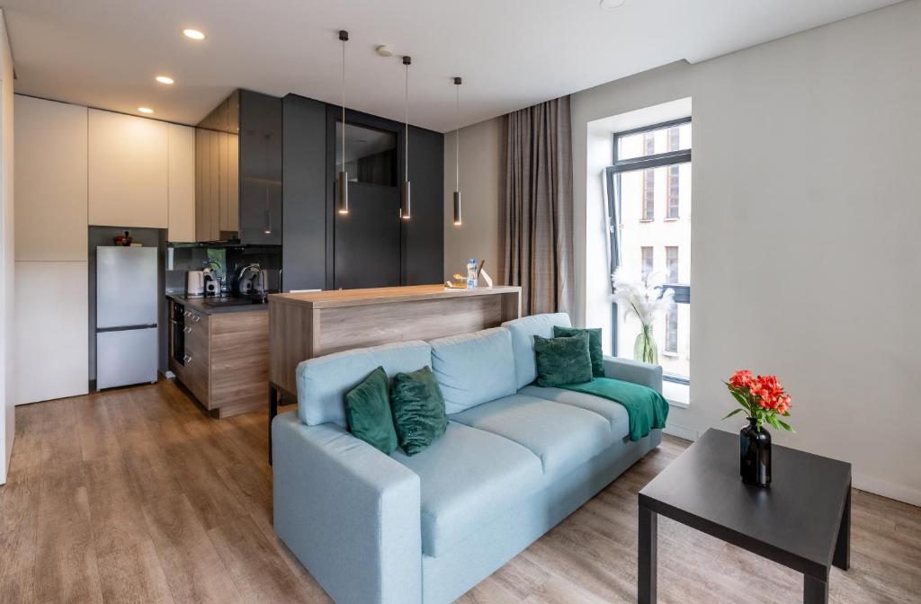 a living room with a blue couch and a kitchen at Urban Nest by Arena and Stadium in Kaunas