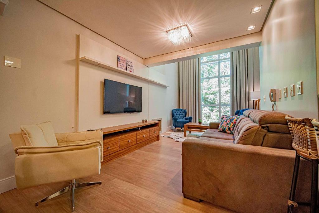 a living room with a couch and a flat screen tv at L'Adresse Réserve 150m R Coberta by Achei Gramado in Gramado