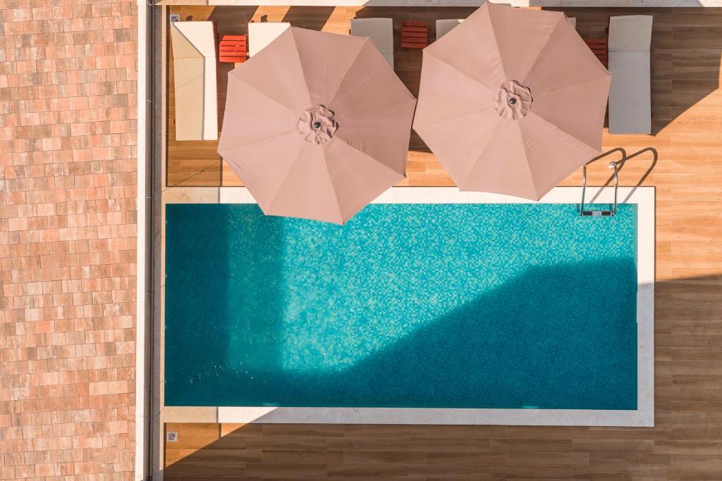 two pink umbrellas hanging over a swimming pool at Villa Tivat in Tivat