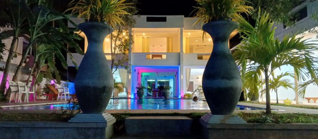 two vases in front of a building with palm trees at Mangroven River View Hotel in Bentota
