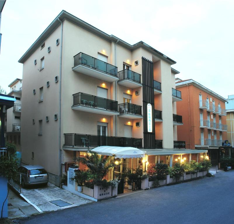 un grande edificio con patio e ombrellone di Hotel Tre Grazie a Rimini