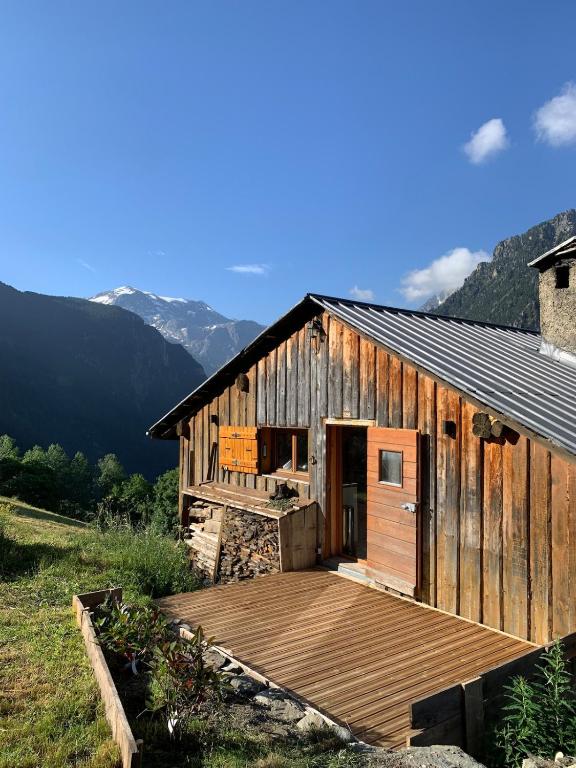 a wooden building with a deck in a field at Chalet Sauce Montagnarde in Planay