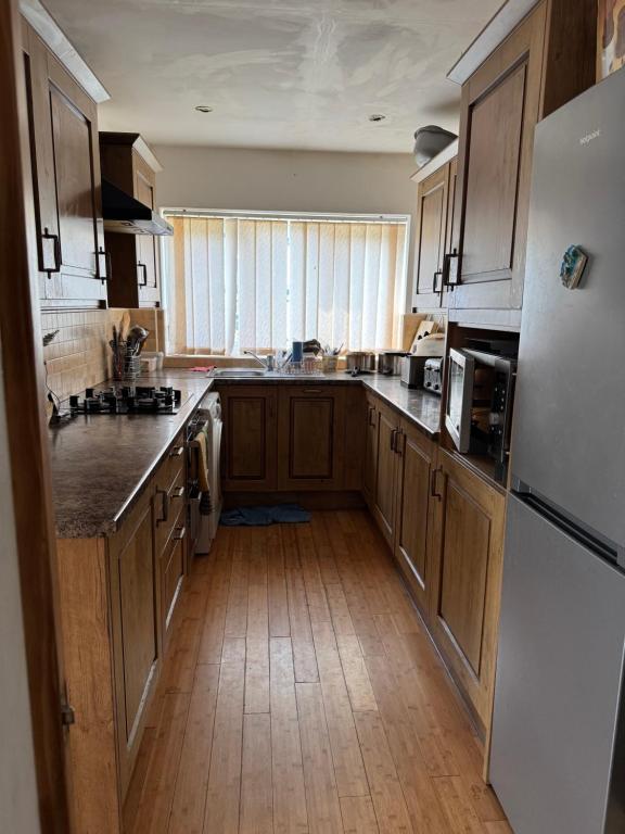 a kitchen with wooden cabinets and a white refrigerator at Bright Double Room near NewCross Hospital in Fallings Park