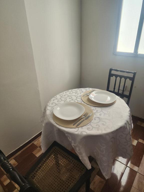 a table with a white table cloth and plates on it at Escuro claro in Campos dos Goytacazes