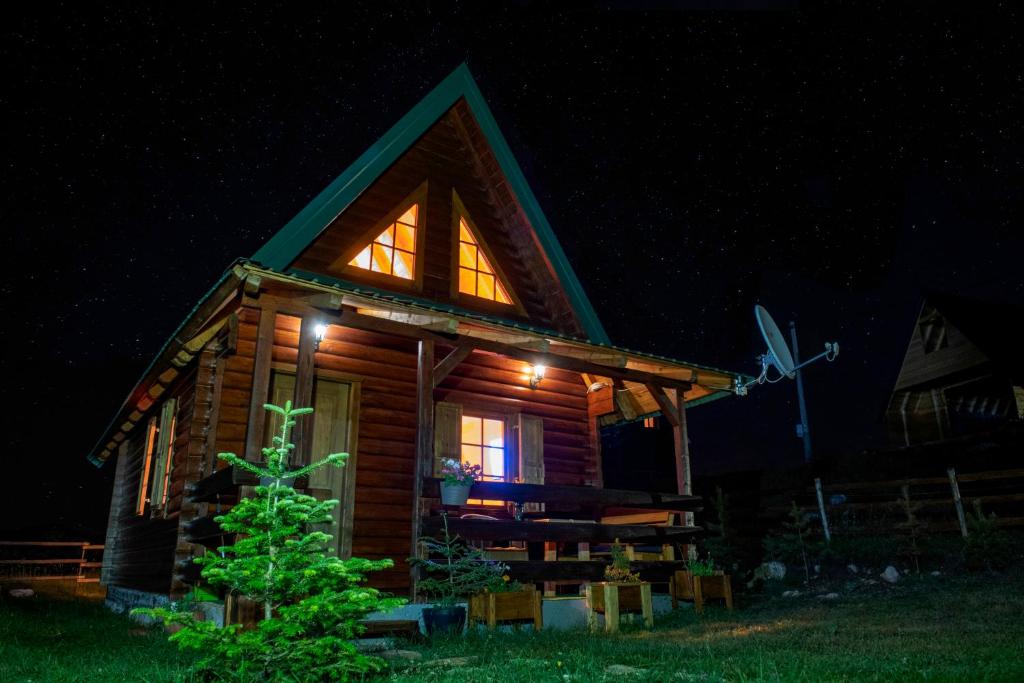 une cabane en rondins allumée la nuit dans l'établissement Wolf Apex, à Žabljak