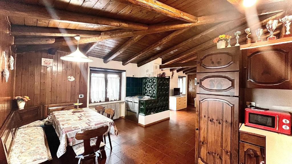 Una cocina y un comedor con una mesa y un televisor. en Appartamento Caprioli, en Pellizzano