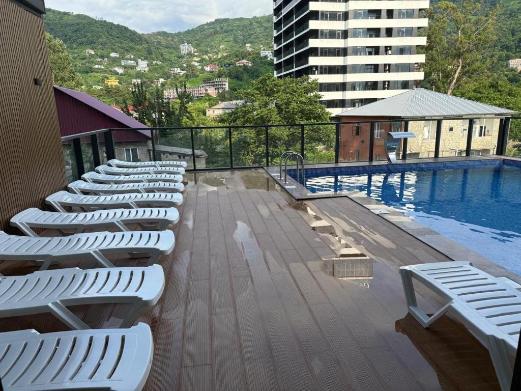 a row of white lounge chairs next to a swimming pool at Thom Tower in Gonio