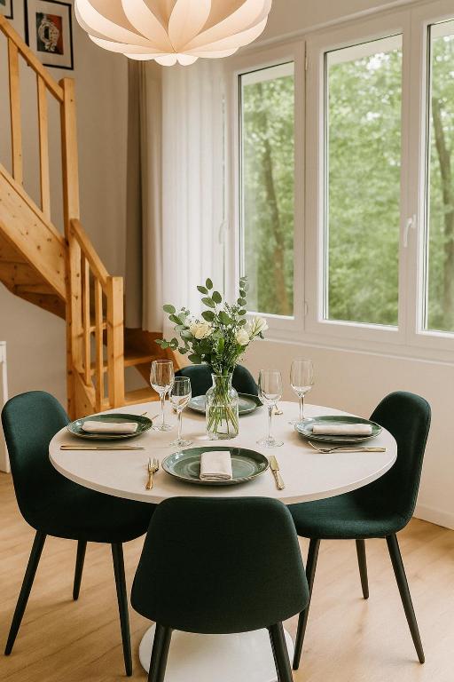 une table à manger avec des chaises vertes et un lustre dans l'établissement Maison Mayel - Havre de Paix Chic & Nature à 30 min de Paris, à Lamorlaye