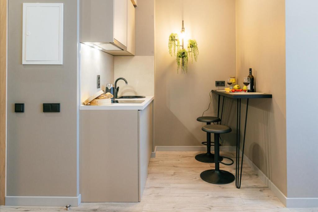 a small kitchen with a sink and a bar stool at Aparthotel Aurum in Riga