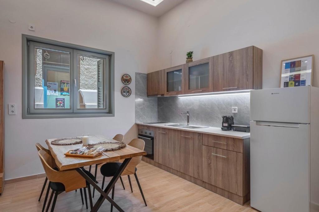 eine Küche mit einem Tisch und einem weißen Kühlschrank in der Unterkunft Nioly Rooms in Ägina Stadt