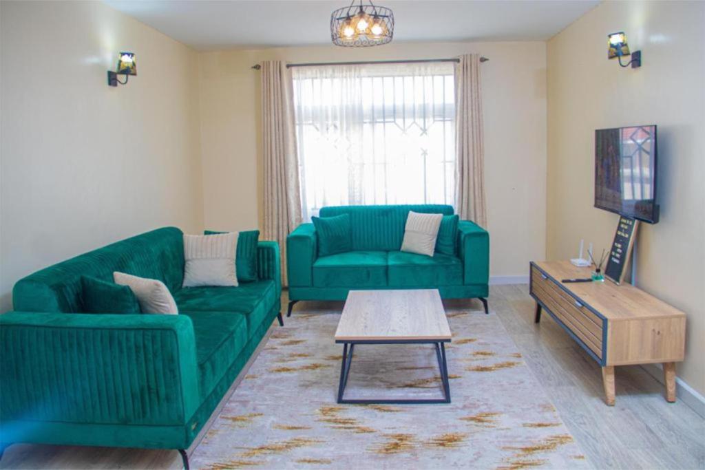a living room with two green couches and a coffee table at Serenity Stays-Venus suite in Nakuru