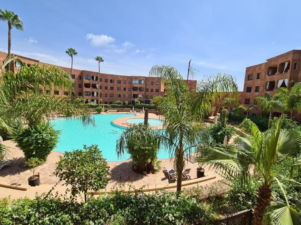 a resort with a swimming pool with palm trees and buildings at Palm river marrackech in Marrakesh