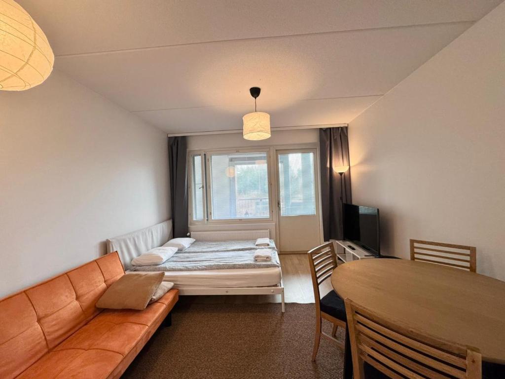 a living room with a bed and a table at Easy Stay Rooms & Apartments near Airport in Vantaa
