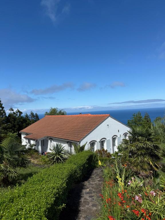 ein weißes Gebäude mit rotem Dach auf einem Hügel in der Unterkunft Villa Ferreirinha in Santa Cruz das Flores