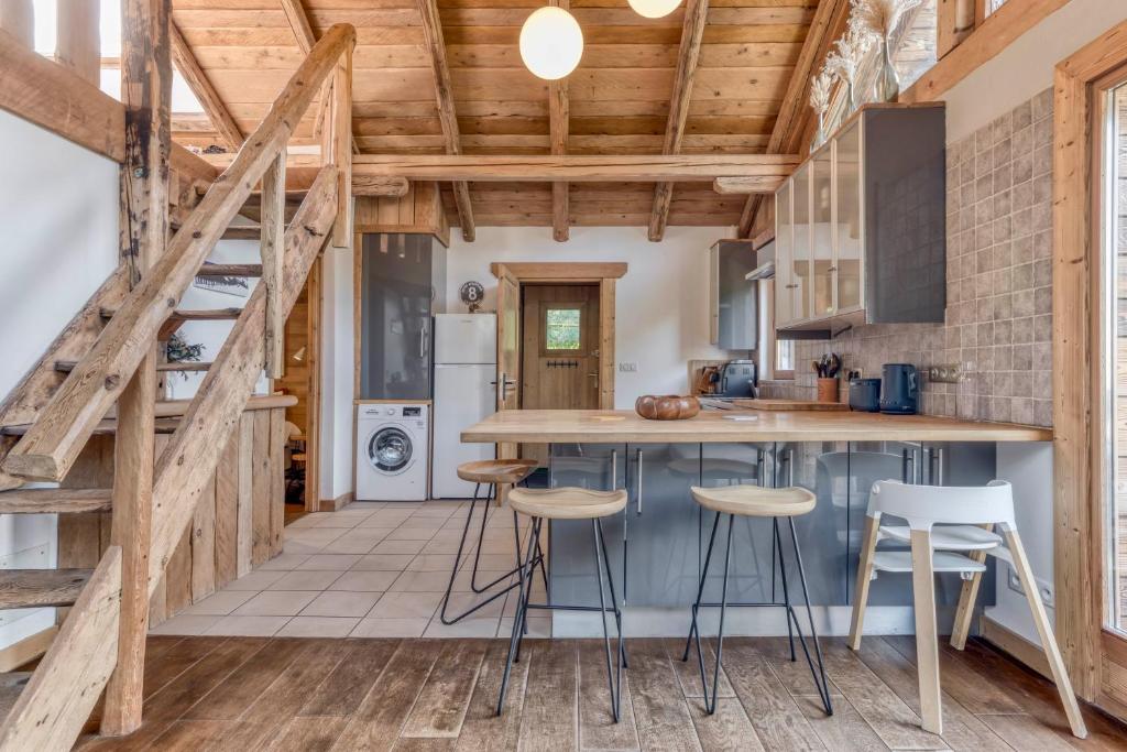- une cuisine avec des plafonds en bois et un comptoir avec des tabourets dans l'établissement AO HOUSE - PRAKKA High Camp, aux Houches