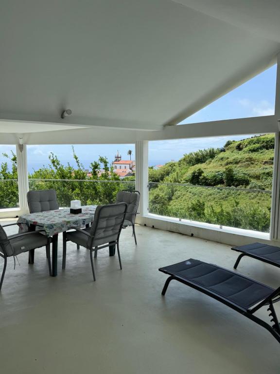 a living room with a table and chairs and a large window at Moradia Terra Chã Sea View 1 to 4 pers in Lomba