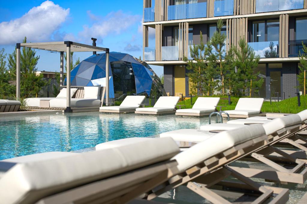 a swimming pool with lounge chairs and an umbrella at Balimood Stay in Palanga