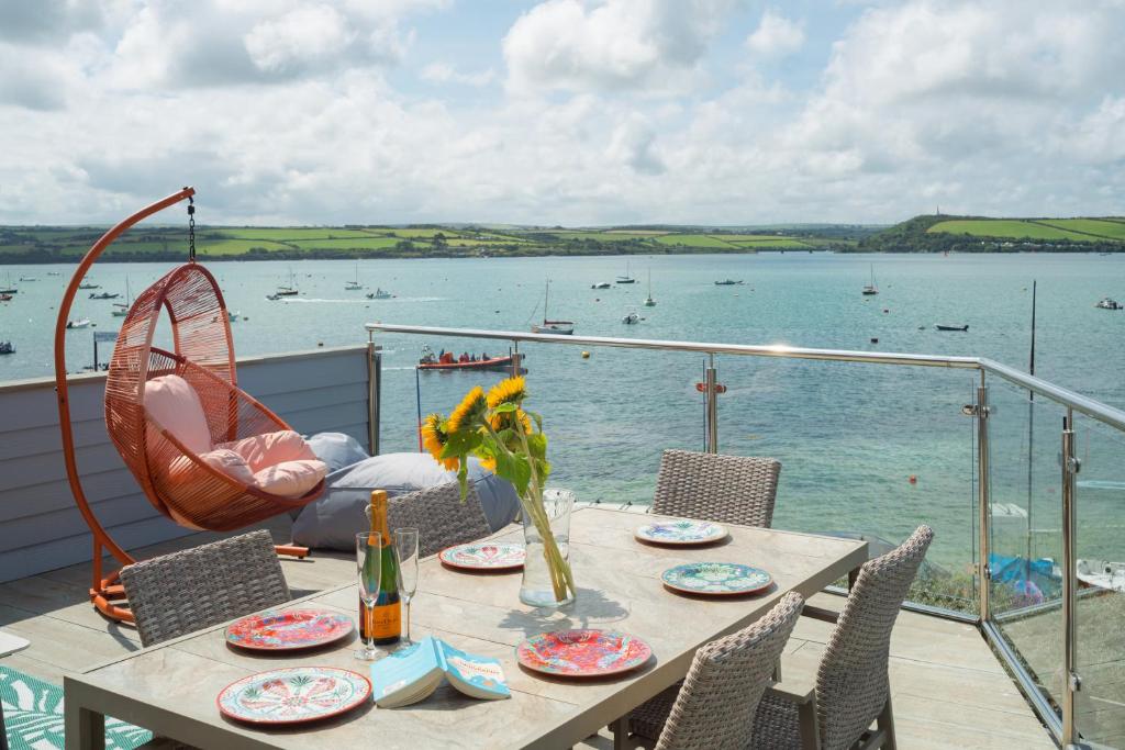 a table on a balcony with a view of the water at FERRYPOINT - 3 Bed Stylish Beachfront Retreat in Padstow