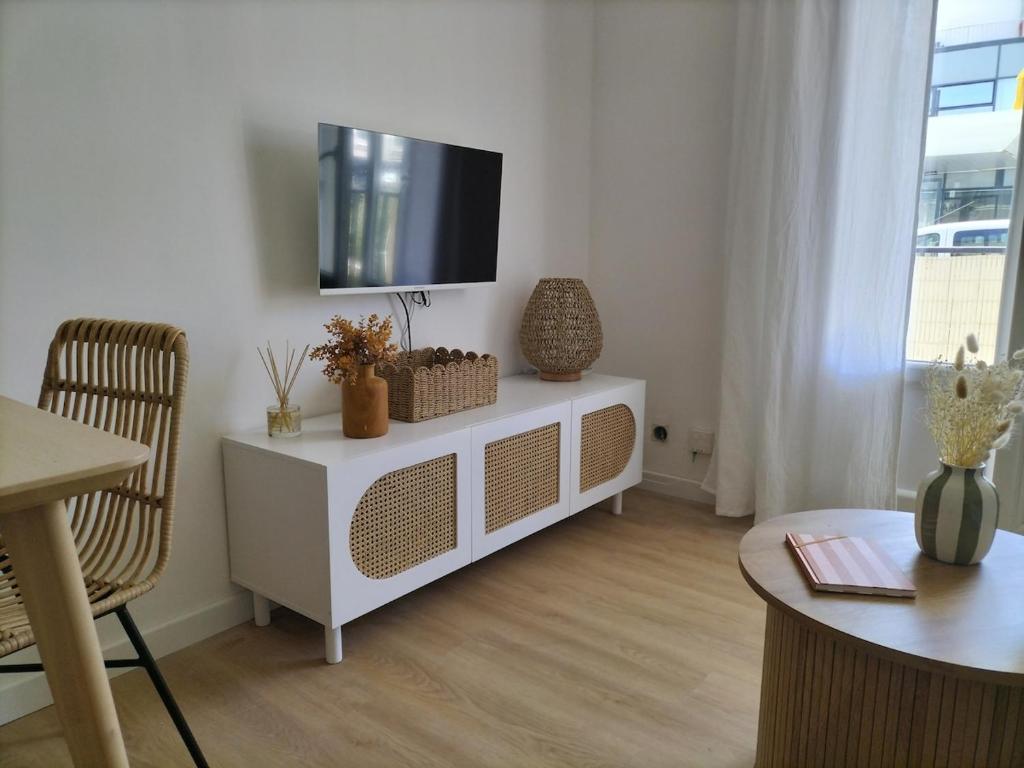a living room with a white cabinet with a tv on it at Appartement Grande Plage St Gilles Croix de Vie - Parking privé in Saint-Gilles-Croix-de-Vie