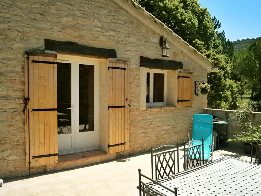 une maison en pierre avec un patio et une chaise bleue dans l'établissement Casa-Simone Les Vieilles Dalles de Pierre, à Malaucène