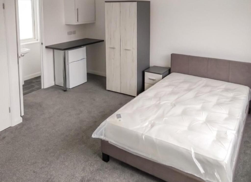 a bedroom with a white bed and a desk at City breaks Corby Uist Walk in Rockingham