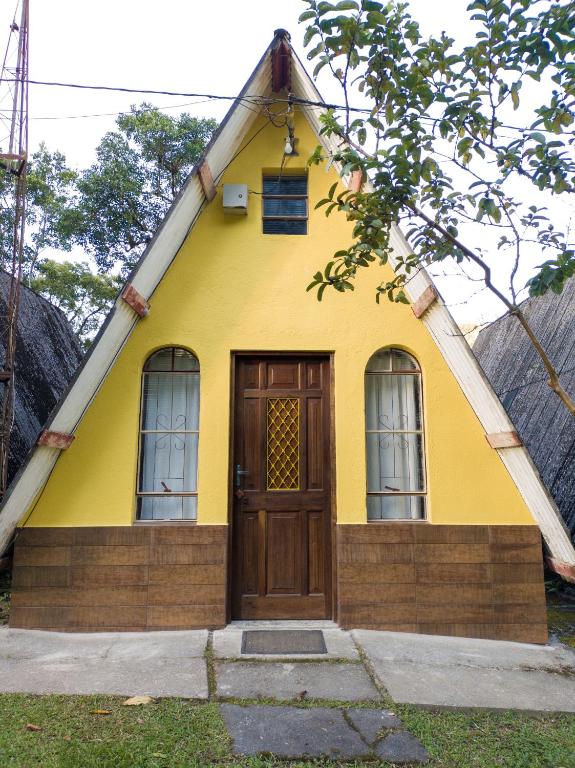 a small yellow house with a wooden door at Recanto Efraim in Tapiraí