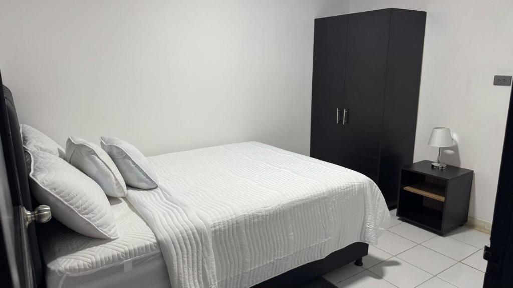 a bedroom with a white bed and a black cabinet at Mami yola 2 in Valledupar