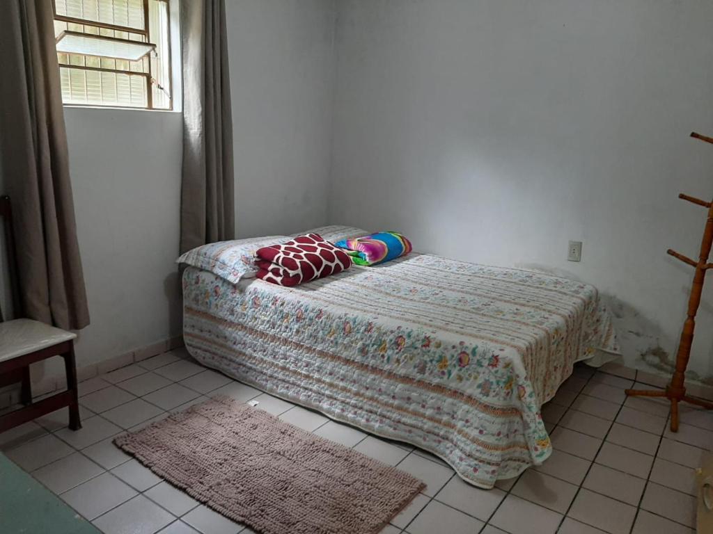 Un dormitorio con una cama con una manta y una ventana. en Casa familiar perto da CEAGA, en Garanhuns
