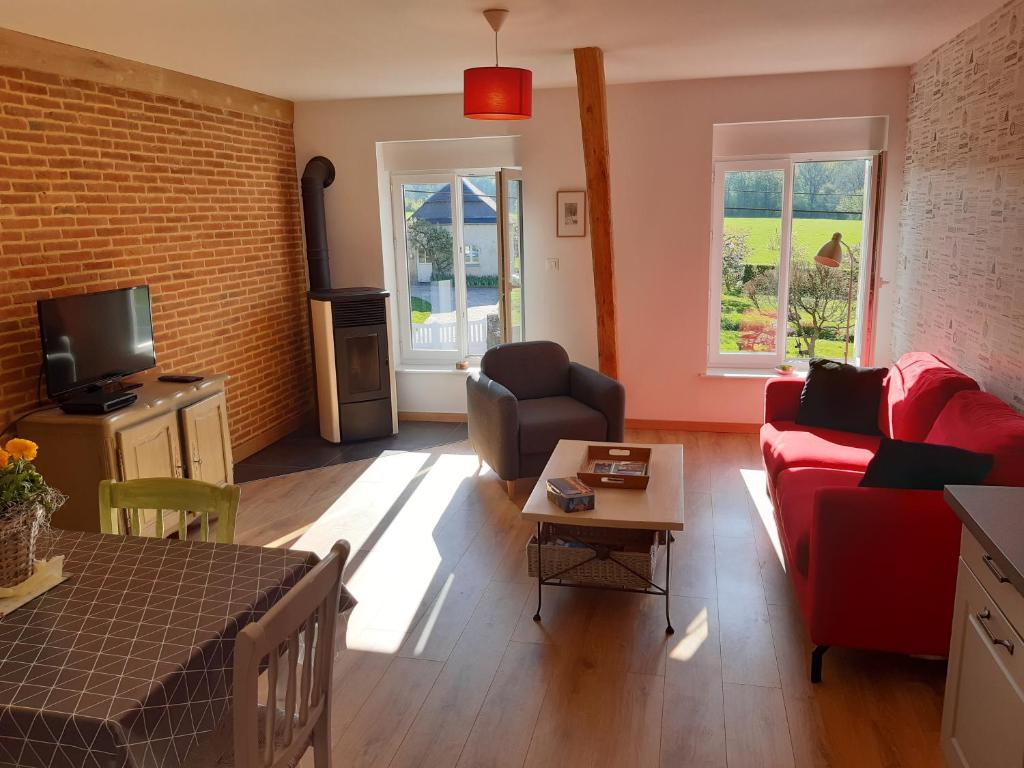 a living room with a red couch and a tv at La grange aux oiseaux in Beaulieu