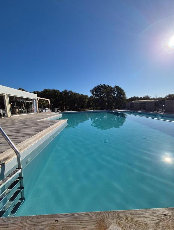 a large blue swimming pool with a wooden deck at Appartement climatisé avec jardin et piscine in Lecci