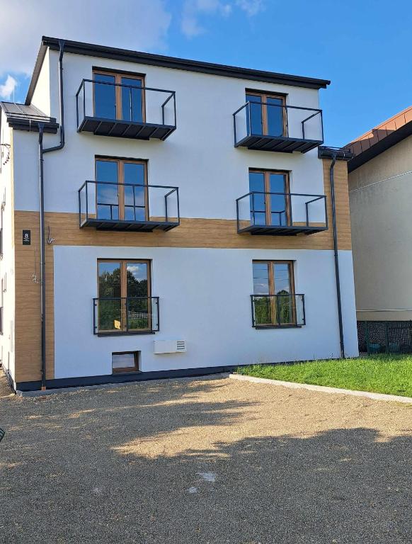 a white building with windows and balconies on it at Niwy8Rooms in Oświęcim