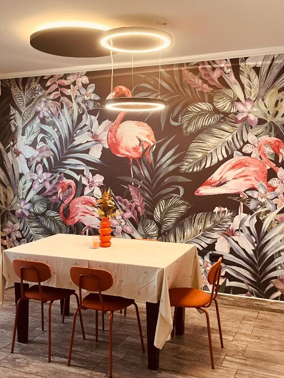 a dining room with a table and pink flamingos wallpaper at ViMaJU in Koper