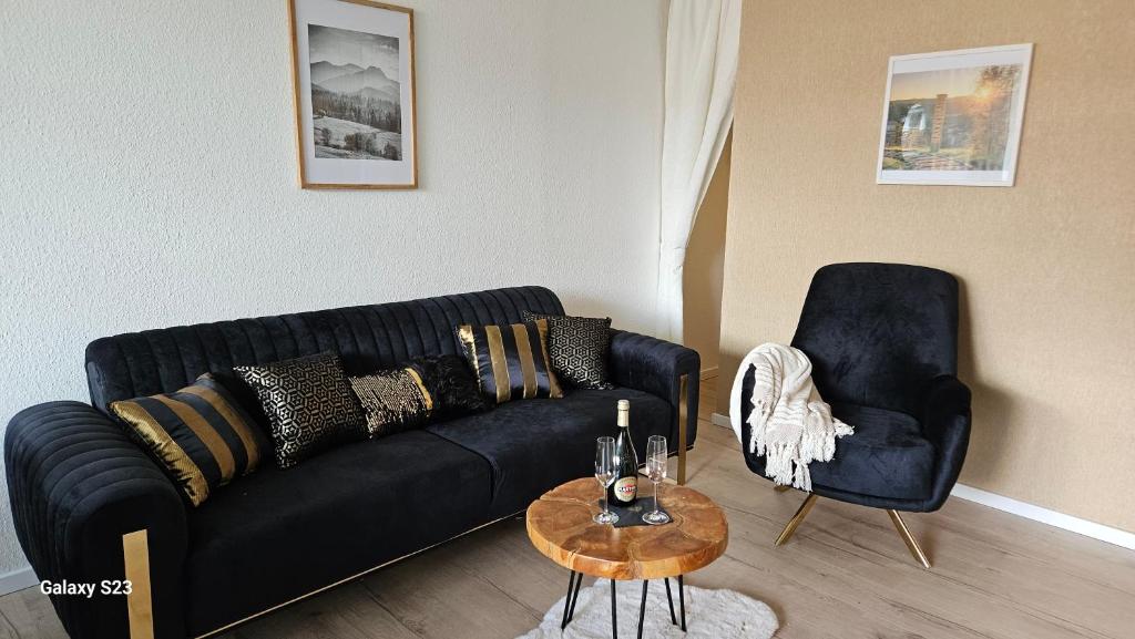 a living room with a black couch and a chair at Harz DeLuxe in Altenau in Altenau