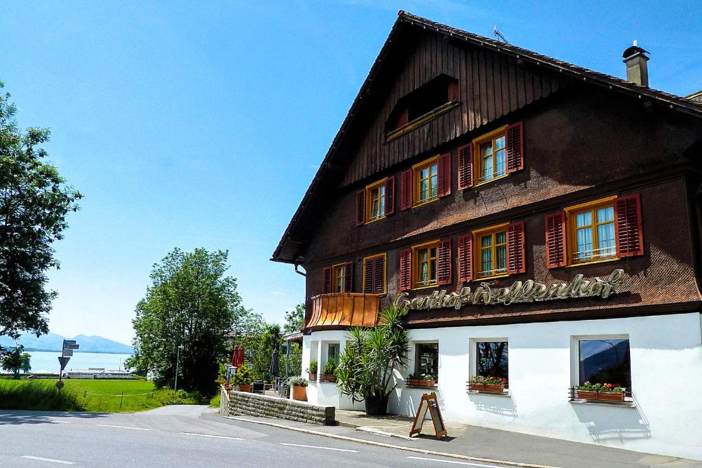 ein großes Holzgebäude mit roten Rollläden auf einer Straße in der Unterkunft Wellenhof Bodensee in Lochau