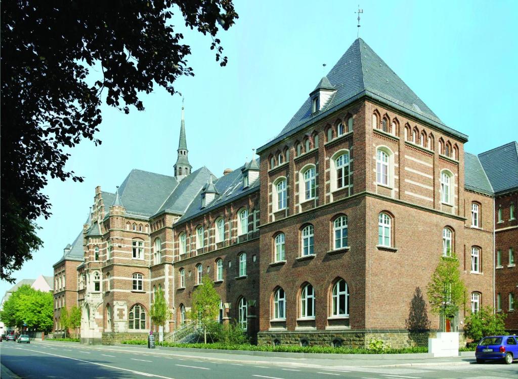 ein großes Backsteingebäude mit einem Kirchturm auf einer Straße in der Unterkunft Collegium Leoninum in Bonn