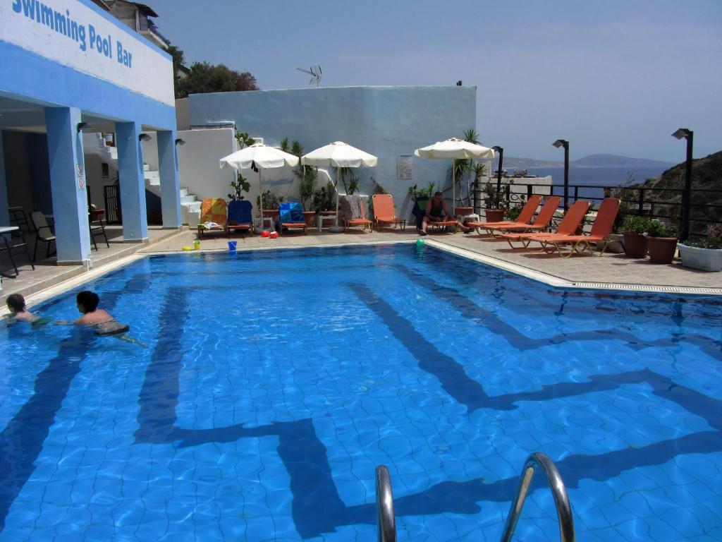 a large blue swimming pool with two people in it at Petra Hotel in Agia Galini